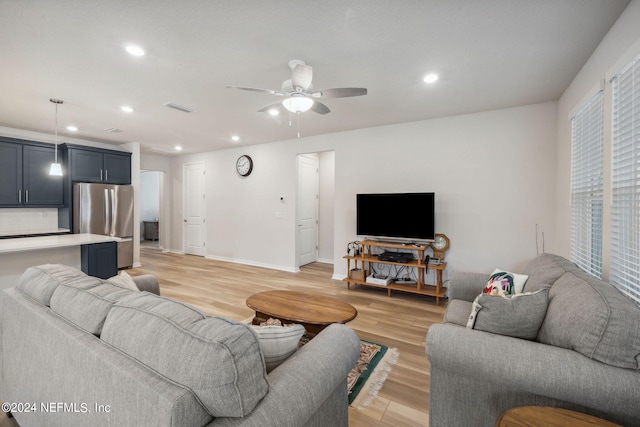 living room featuring light wood-type flooring, ceiling fan, visible vents, and recessed lighting