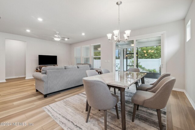 dining space featuring a healthy amount of sunlight, ceiling fan with notable chandelier, and light wood-type flooring