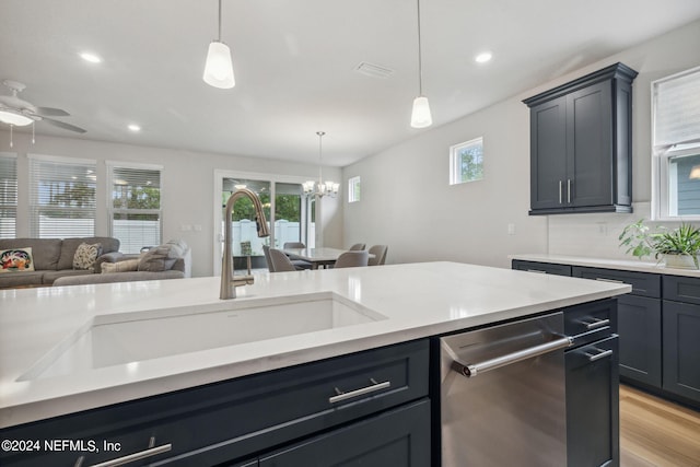 kitchen with pendant lighting, open floor plan, stainless steel dishwasher, and light countertops