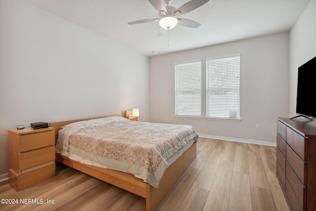 bedroom with light wood-style flooring, baseboards, and a ceiling fan