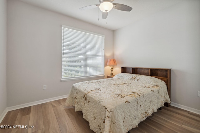 bedroom with ceiling fan, wood finished floors, and baseboards