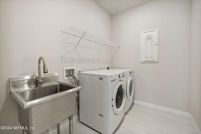 clothes washing area with a sink, laundry area, washing machine and clothes dryer, and baseboards