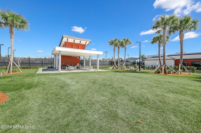 view of community with a lawn, a patio area, and fence