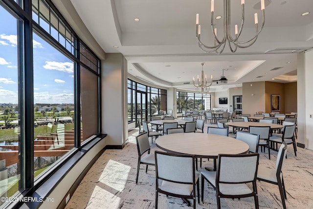 dining space featuring a chandelier, a raised ceiling, visible vents, and baseboards