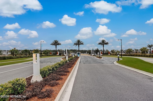 view of road with curbs, a gated entry, and street lights