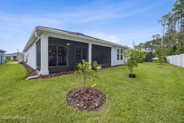 back of house featuring a yard and a sunroom