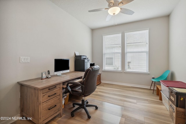 home office featuring a ceiling fan, light wood-style flooring, baseboards, and a textured ceiling