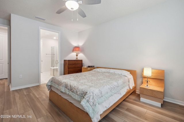 bedroom with baseboards, visible vents, a ceiling fan, ensuite bath, and wood finished floors