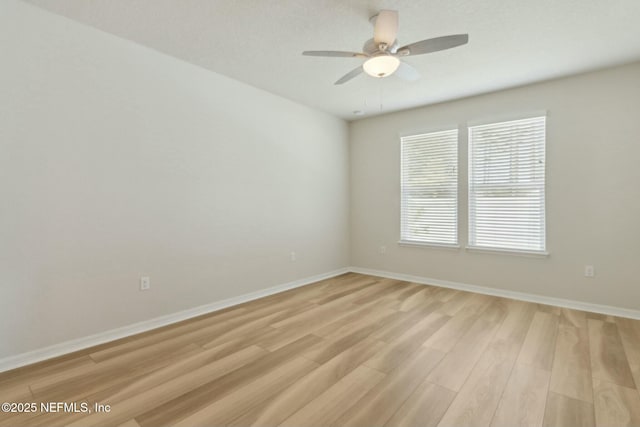 empty room featuring light wood finished floors, baseboards, and a ceiling fan