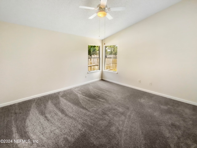 empty room featuring ceiling fan, vaulted ceiling, and carpet