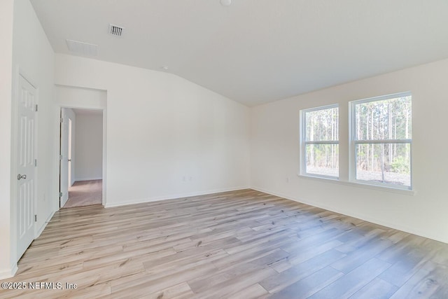 spare room featuring lofted ceiling and light hardwood / wood-style flooring