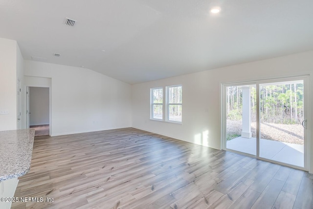 spare room with a wealth of natural light, light hardwood / wood-style floors, and vaulted ceiling