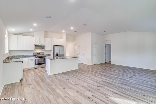 kitchen with sink, light hardwood / wood-style flooring, a kitchen island, stainless steel appliances, and white cabinets