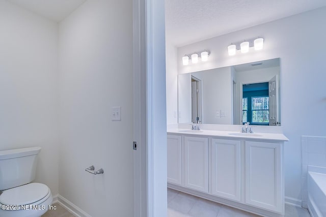 bathroom featuring tile patterned flooring, vanity, a textured ceiling, toilet, and a bathing tub