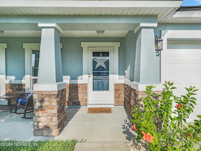 property entrance featuring covered porch and a garage