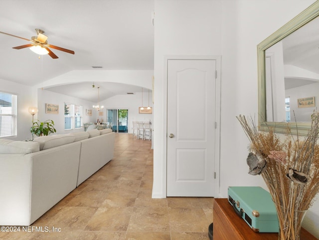 tiled living room with ceiling fan with notable chandelier and lofted ceiling