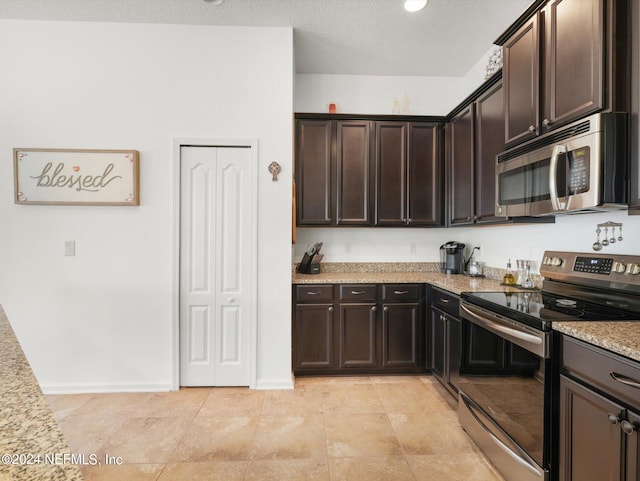 kitchen with light tile patterned flooring, appliances with stainless steel finishes, and dark brown cabinets