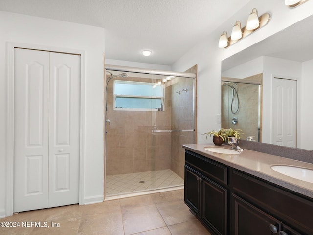 bathroom featuring tile patterned floors, dual bowl vanity, an enclosed shower, and a textured ceiling