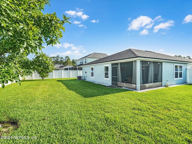 rear view of house with cooling unit, a sunroom, and a lawn