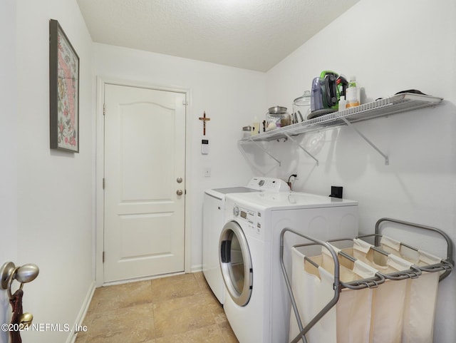 clothes washing area with a textured ceiling, washer and clothes dryer, and light tile patterned floors