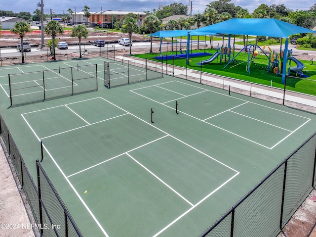 view of tennis court featuring a playground