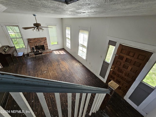foyer with wood-type flooring, a fireplace, ceiling fan, and a textured ceiling