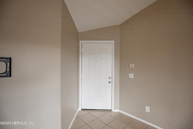 interior space featuring light tile patterned floors, baseboards, and vaulted ceiling