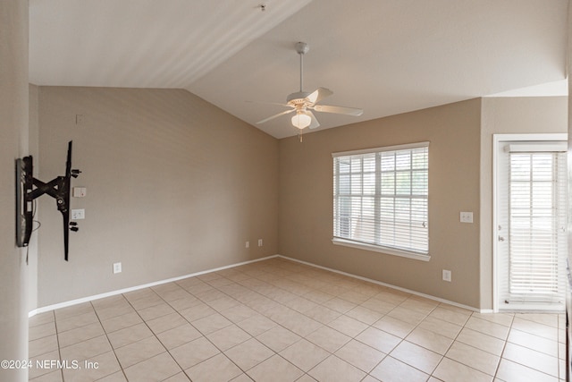 empty room featuring vaulted ceiling, light tile patterned flooring, a ceiling fan, and baseboards