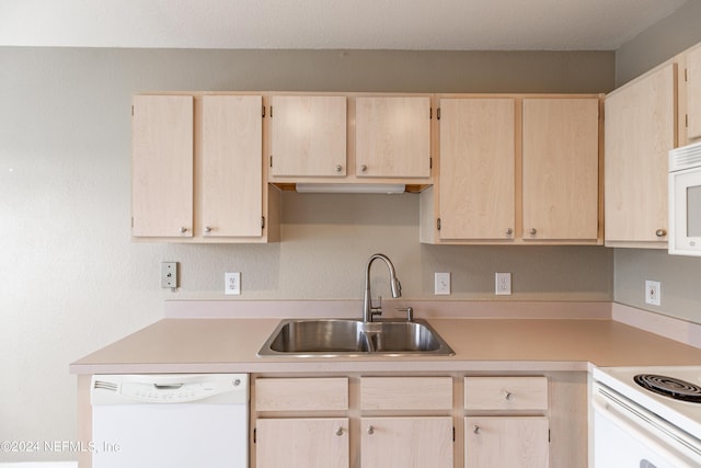 kitchen featuring white appliances, light brown cabinets, light countertops, and a sink