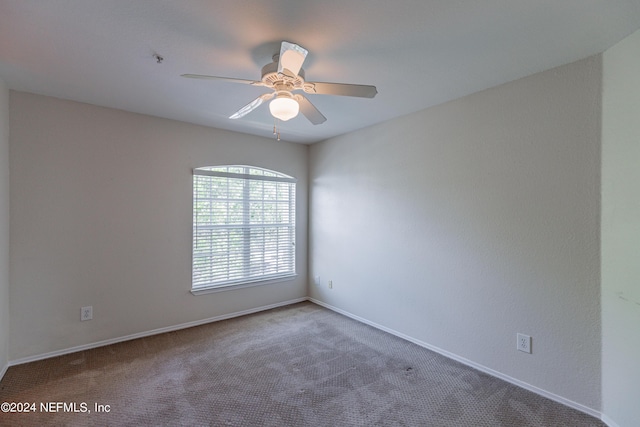 carpeted spare room with ceiling fan and baseboards