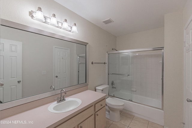 bathroom with visible vents, toilet, tile patterned flooring, combined bath / shower with glass door, and vanity