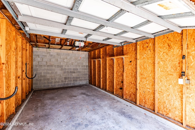 garage featuring concrete block wall and a garage door opener