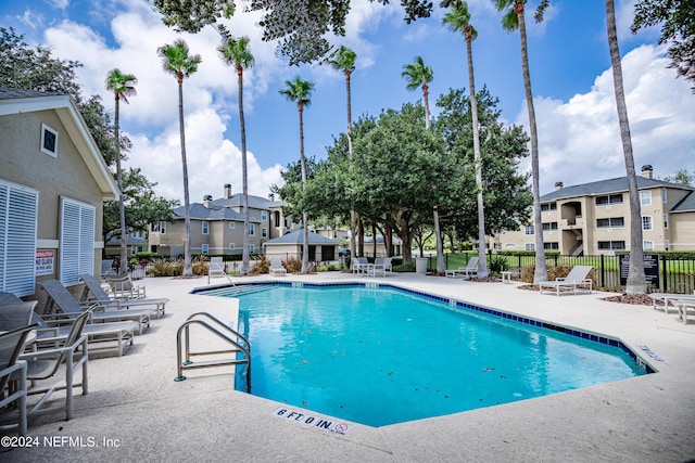 pool with a patio area, a residential view, and fence