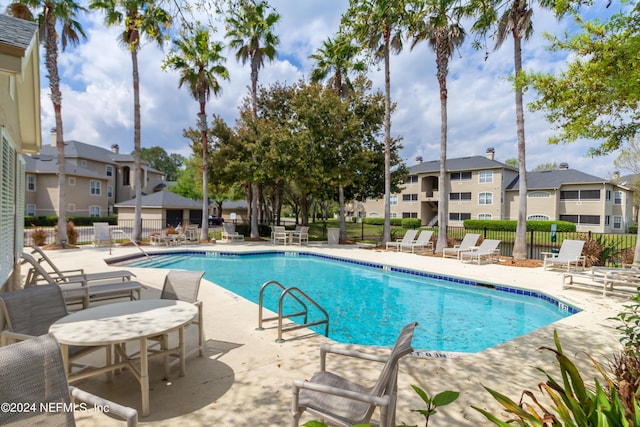 community pool featuring a residential view, fence, and a patio