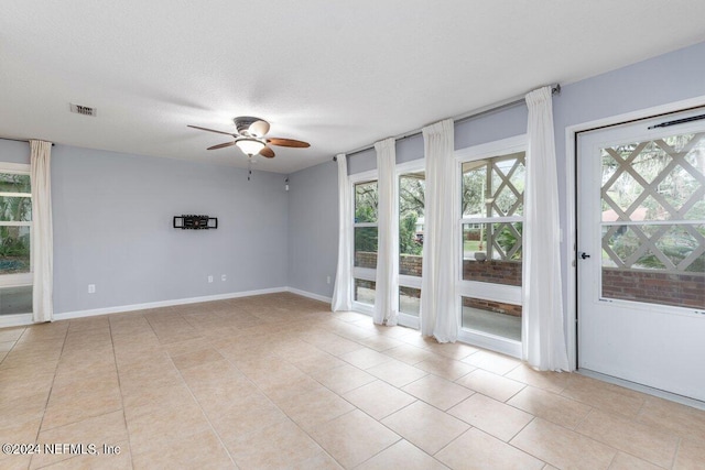 spare room featuring ceiling fan, a healthy amount of sunlight, and light tile patterned floors