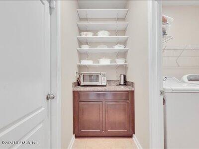 bar featuring washer / dryer and light tile patterned floors