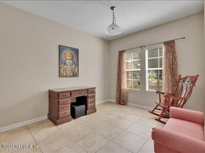 living area with light tile patterned floors, baseboards, and a textured ceiling