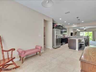 kitchen with decorative light fixtures, stainless steel fridge, light tile patterned flooring, and a kitchen island