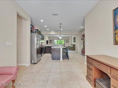 kitchen featuring a breakfast bar, a center island, light tile patterned floors, ceiling fan, and refrigerator