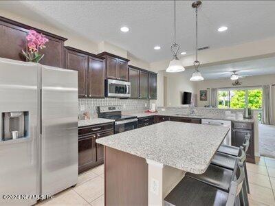 kitchen featuring kitchen peninsula, stainless steel appliances, light tile patterned floors, and tasteful backsplash