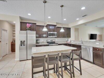 kitchen with tasteful backsplash, dark brown cabinets, a kitchen bar, hanging light fixtures, and stainless steel appliances