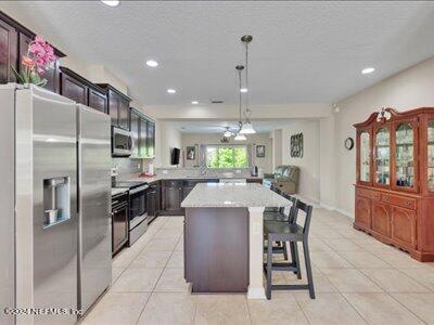 kitchen with pendant lighting, a breakfast bar, a kitchen island, appliances with stainless steel finishes, and light tile patterned flooring