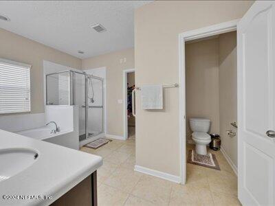 full bathroom featuring toilet, tile patterned flooring, separate shower and tub, and vanity