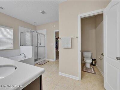 full bath with tile patterned floors, visible vents, toilet, a stall shower, and vanity