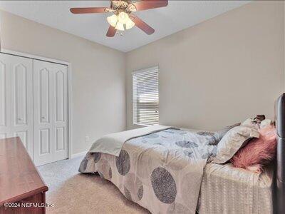 bedroom featuring ceiling fan, a closet, and light carpet