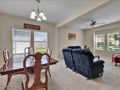 carpeted dining room featuring a wealth of natural light, a textured ceiling, and ceiling fan with notable chandelier