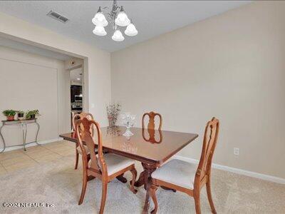 carpeted dining space featuring a notable chandelier