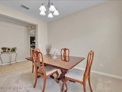 dining room featuring visible vents, light carpet, baseboards, and an inviting chandelier