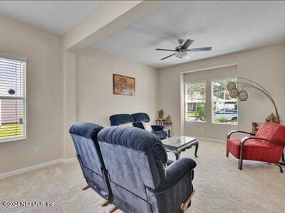 living room with ceiling fan, baseboards, and carpet