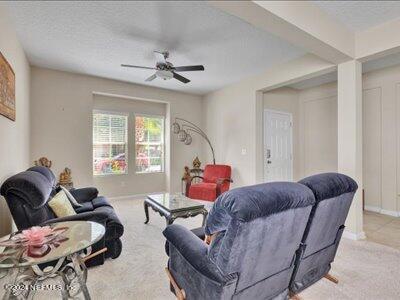 living room with ceiling fan and light colored carpet